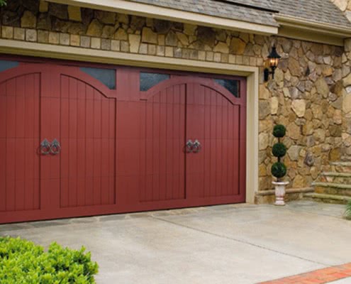 Rock house with red wood Amarr garage doors with window panels on top.