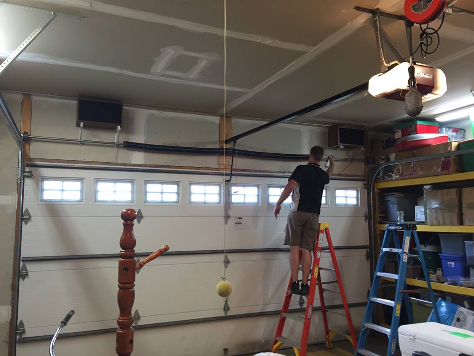 Affordable Professional Garage Door Tune Up In Minnesota Elite Garage Door Technician Standing On A Ladder Tuning Up