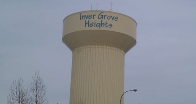 Off white water tower for inver grove heights with blue lettering and a blue sky in the background.
