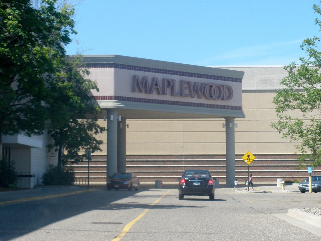 The outside of Maplewood Mall with parking lot and a side street with cars on the road with a cross walk.